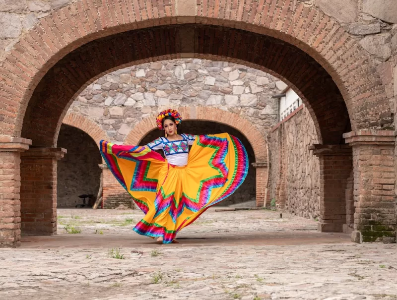 A young woman wearing traditional folkloric dress dances in Oaxaca on cinco de mayo